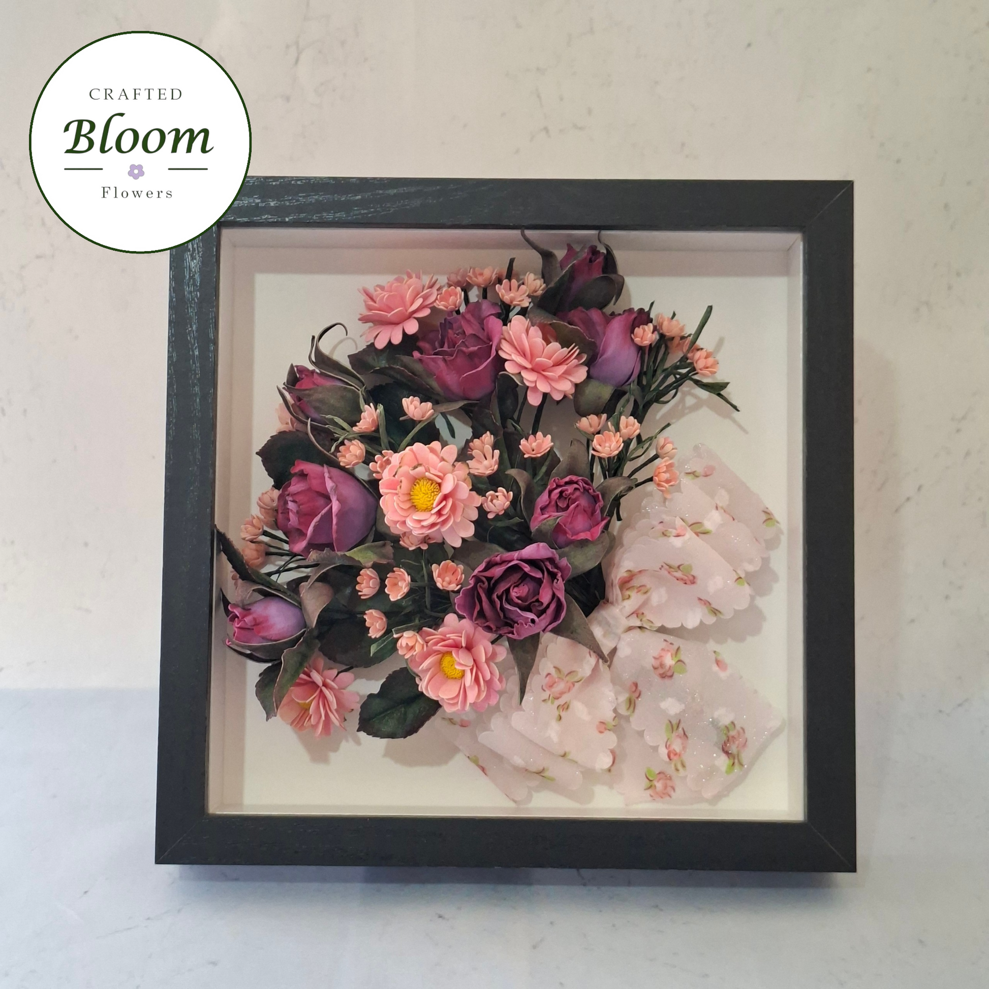 Handmade Foamiran flower shadow box frame with purple roses and pink daisy flowers arranged inside a black frame for elegant well home décor.
